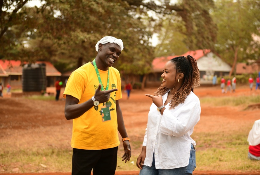 Two Food4Education staff smile while stand outside a community kitchen in Africa.